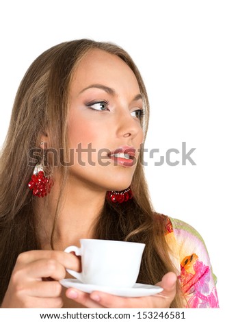 Girl in red earrings drinking tea on white background
