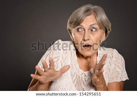 Scared senior woman standing on dark background