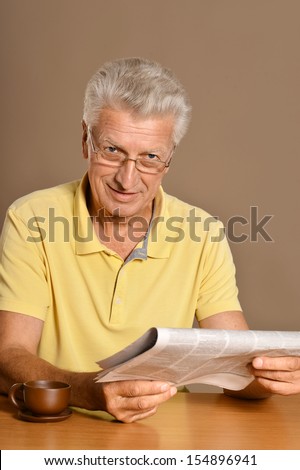 Senior man reading newspaper at a table