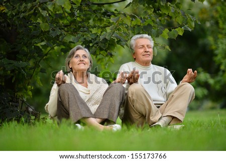 Elderly couple sitting on the grass in lotus pose