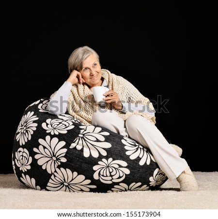 Happy senior woman drinking tea on black background