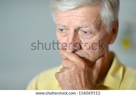 Intelligent elderly man in full vigor thinking on gray background