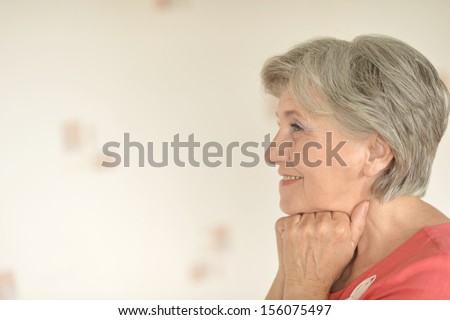 Portrait of smiling elderly woman on gray background