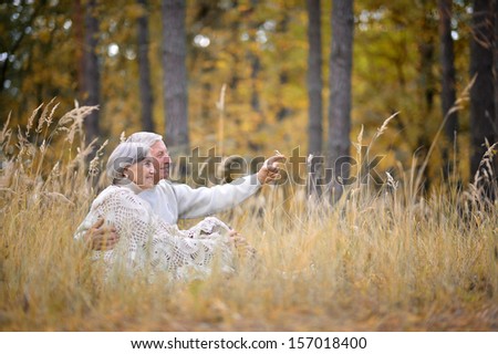 Happy Elderly Couple Sitting In Autumn Park