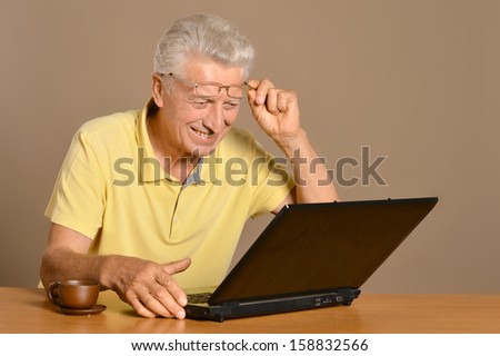 happy old man with laptop at the table