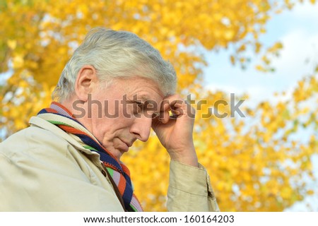 Portrait of thoughtful elderly man on yellow autumn background
