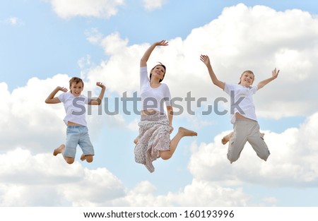 Happy family jumping on a background of blue sky and clouds