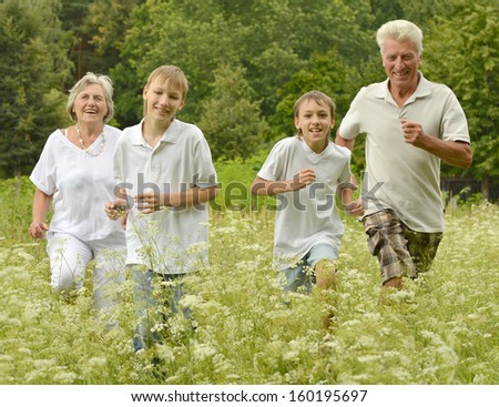 Older man and woman running with their grandchildren outdoors