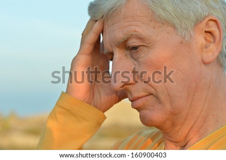 Thoughtful elder man on blue sky background