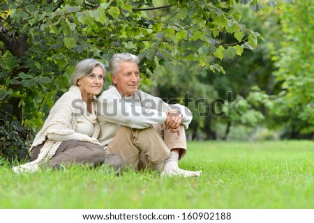 happy elder couple resting on grass at nature