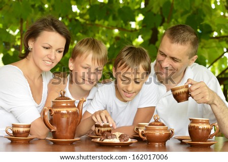 happy family drinking tea in the garden in summer