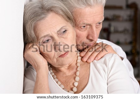 Close-up portrait of a sad elder couple on white background
