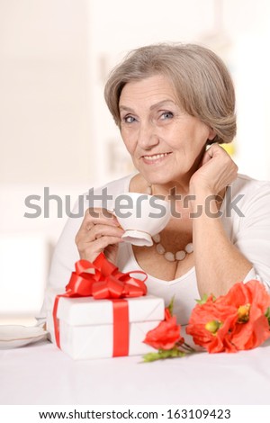 Portrait of happy elderly woman with gift at home