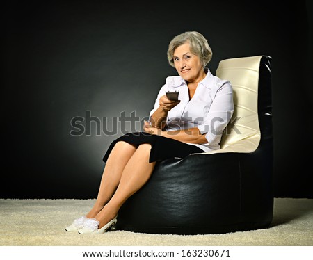 senior woman watching tv on dark background