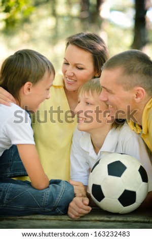 Portrait of happy family at wooden table with football bal