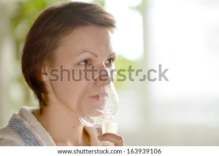 Portrait of a young woman doing inhalation at home
