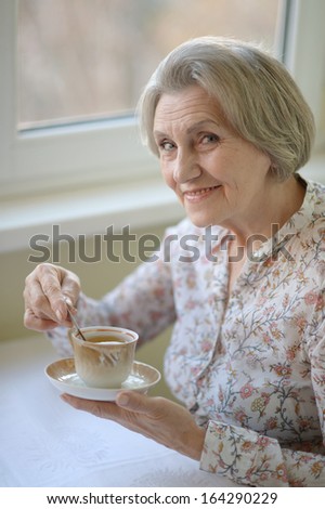 Beautiful elderly woman in at home with cup