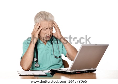 Senior upset doctor sitting at table with notebook. Isolated white background