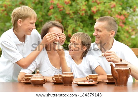 Happy family drinking tea at table outdoors in summer time