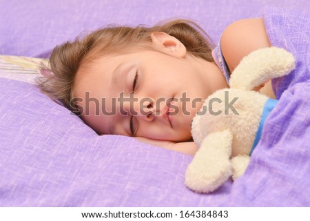 Cute little girl sleeping with a toy in her bed