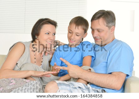 Family of three playing rock paper scissors at home