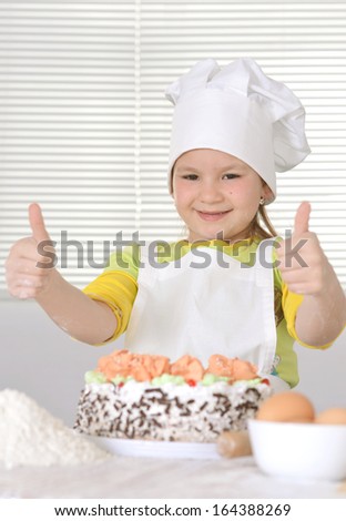 Lovely girl in a chef\'s hat with a beautiful sweet cake