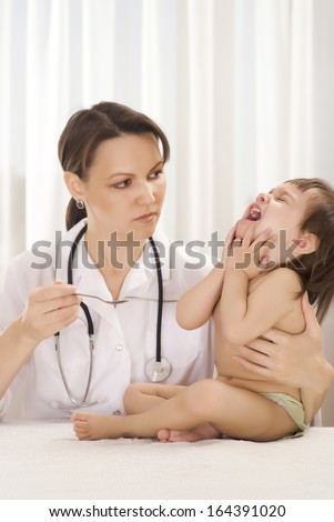 Doctor pediatrician with a crying girl in his office