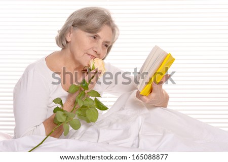 Beautiful older woman resting in the bedroom with book