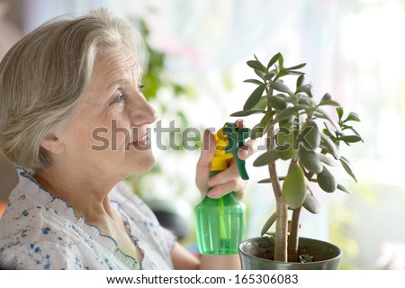 Senior woman watering plant at home