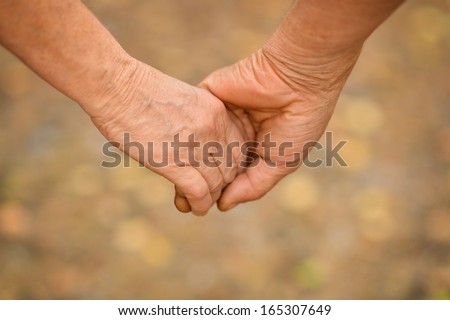 Hands Held Together On A Natural Yellow Background