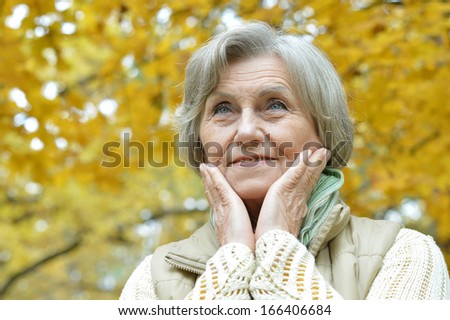 elderly woman in a warm sweater for a walk in the park in autumn