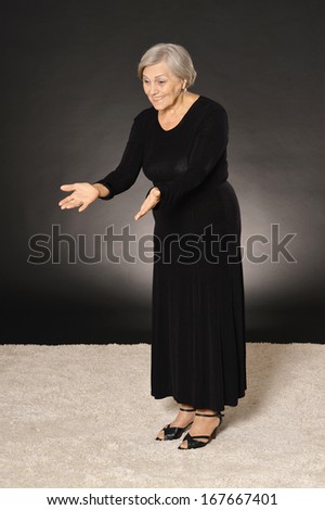 Elegant elderly woman in black dress smiling on dark background