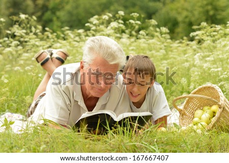 Grandfather and his grandson reading book outdoor
