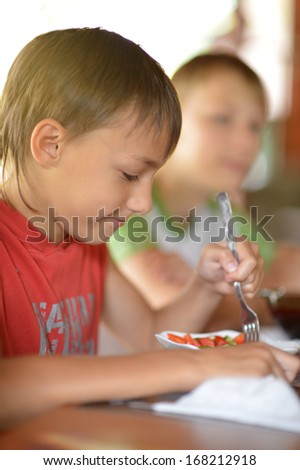 Little boy eating at home with fork from plate