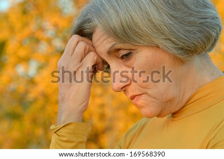 Nice sad old woman on the autumn background