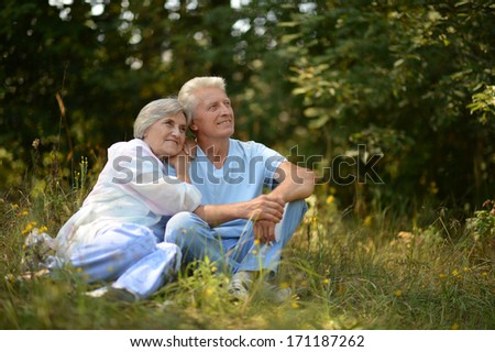 Happy Elder Couple Resting On Grass At Nature