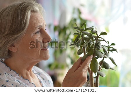 Senior woman with plant at home