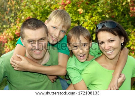 Cheerful Family In Green Shirts Walking In The Summer Park