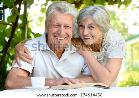 Nice Elderly Couple Sitting At Table During Summer