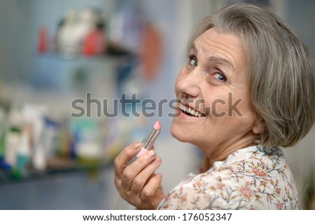 Beautiful portrait of an elder woman making up with lipstick
