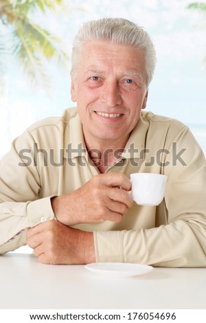 Nice old man drinking coffee at table
