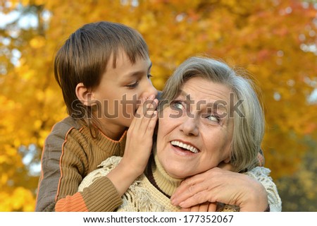 Grandmother and grandson take a walk during the fall of the leaves in the park