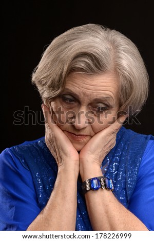 Pensive elderly woman on a black background