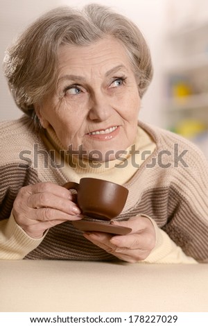 Portrait of aged woman drinking coffee on brown background