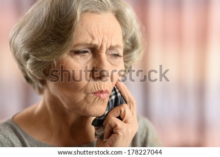 Elderly woman having bad tooth pain isolated on colored background