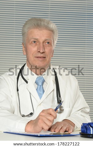 Elderly doctor at a table on a white background