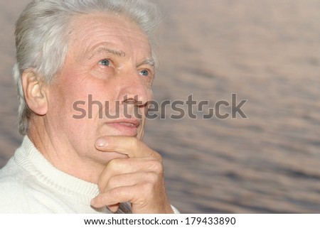 Thoughtful caucasian old man on sea background