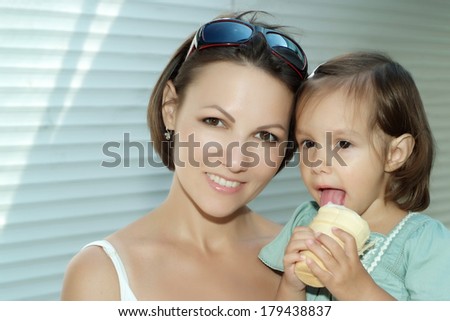 Little cute girl eating ice cream with her mother