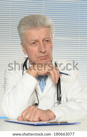 Elderly doctor at a table on a white background
