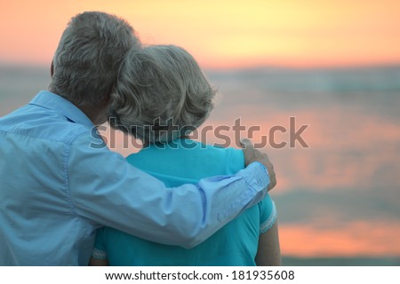 Elderly couple in love at sunset on a summer evening watching sea